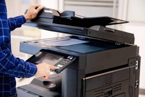 Person using the control panel of a modern office multifunction printer and copier
