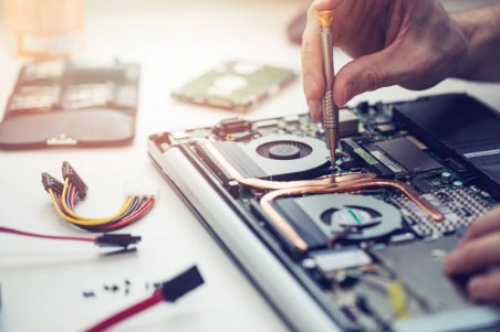 Technician working on the internal components and cables of a disassembled laptop
